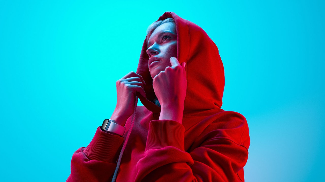 Woman in red hoodie under vibrant neon cyan lighting.