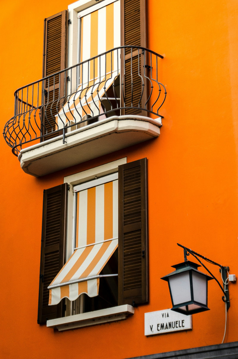 Orange building with striped awnings on “Via V. Emanuele”.