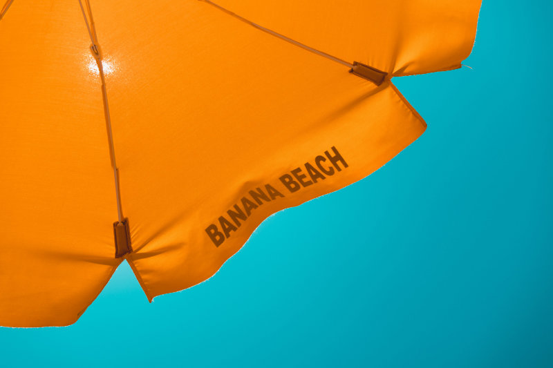 Orange Banana Beach umbrella against a bright blue sky.